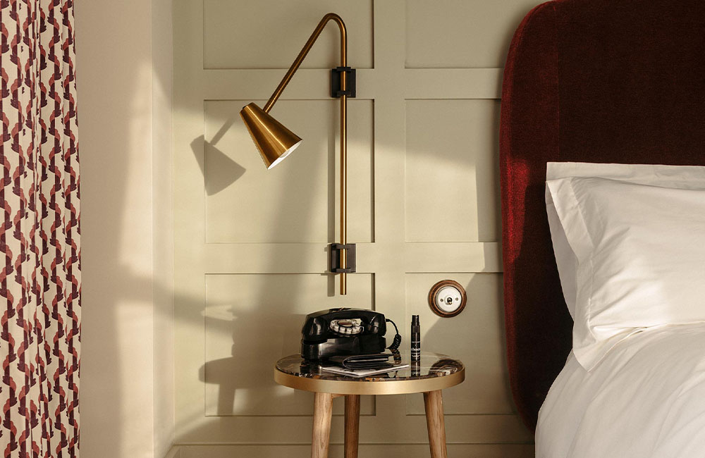 Side view of a bed and bedside table with a radio and reading lamp.