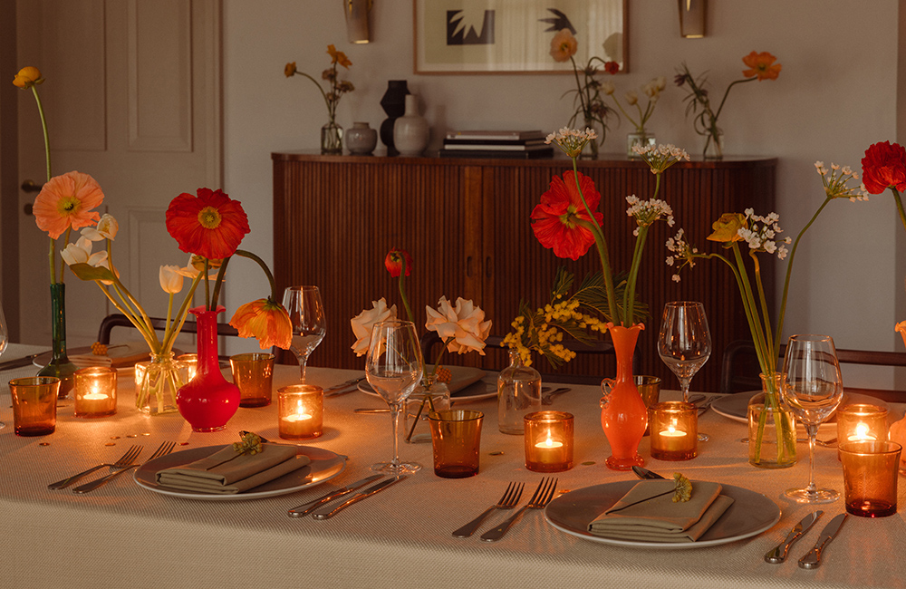 Candlelit dining table with red flowers