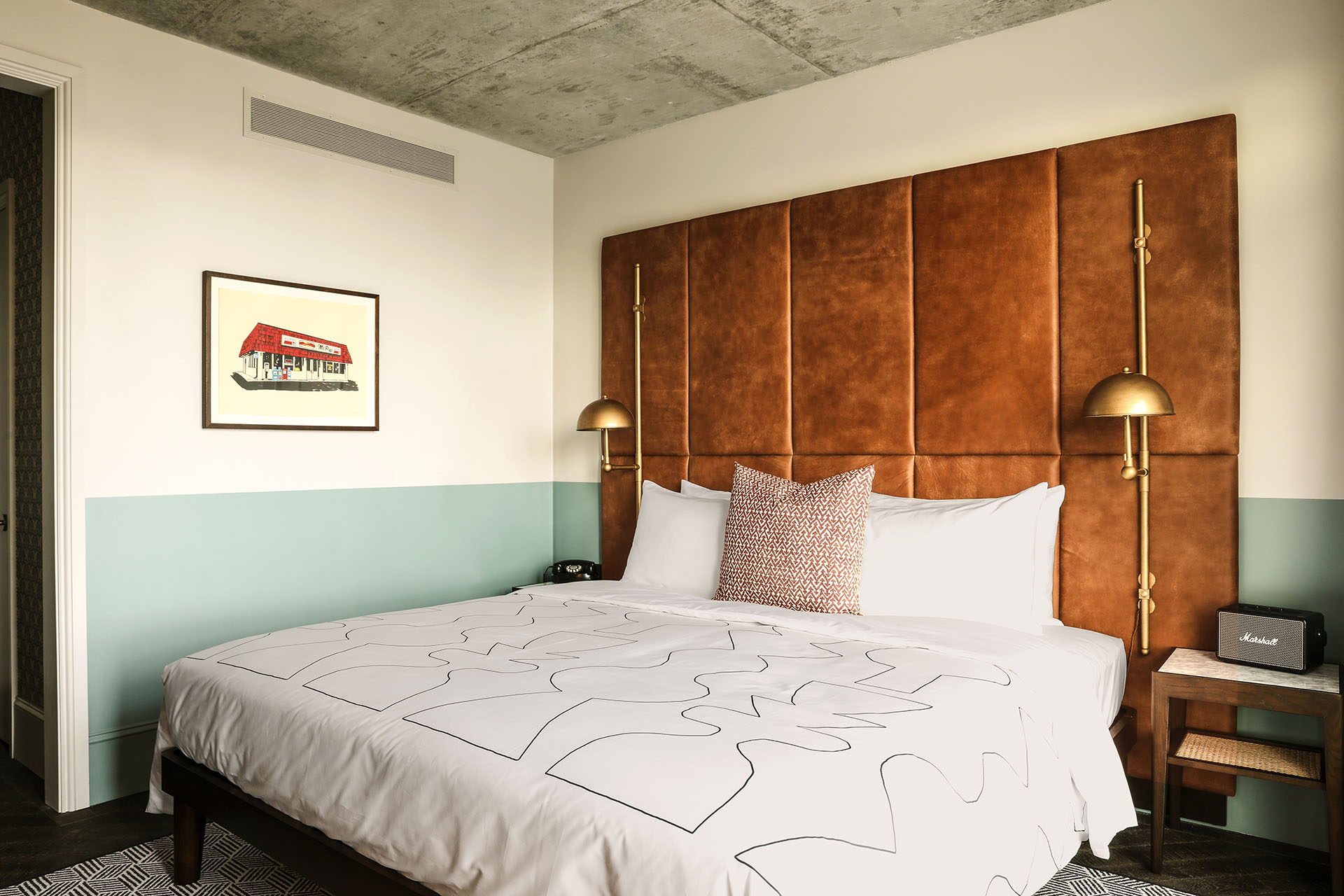 King sized bed with a telephone and Marshall speaker either side, with modern artwork on the wall