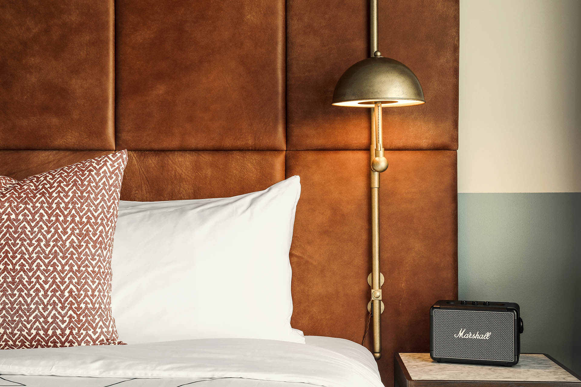 A Marshall bluetooth speaker sits on the table beside the bed