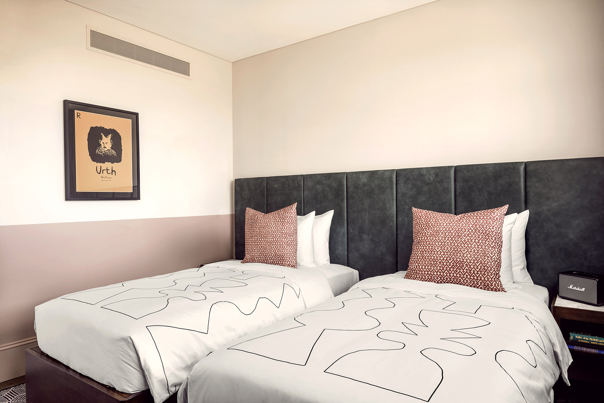 Two twin beds side by side in a hotel room, with modern artwork on the wall