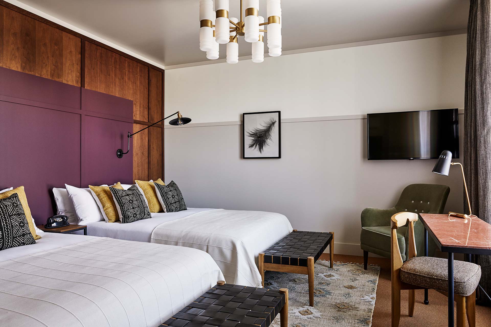 The two queen beds are separated by a table with a telephone on it, and the room also features a TV, lounge chair and desk