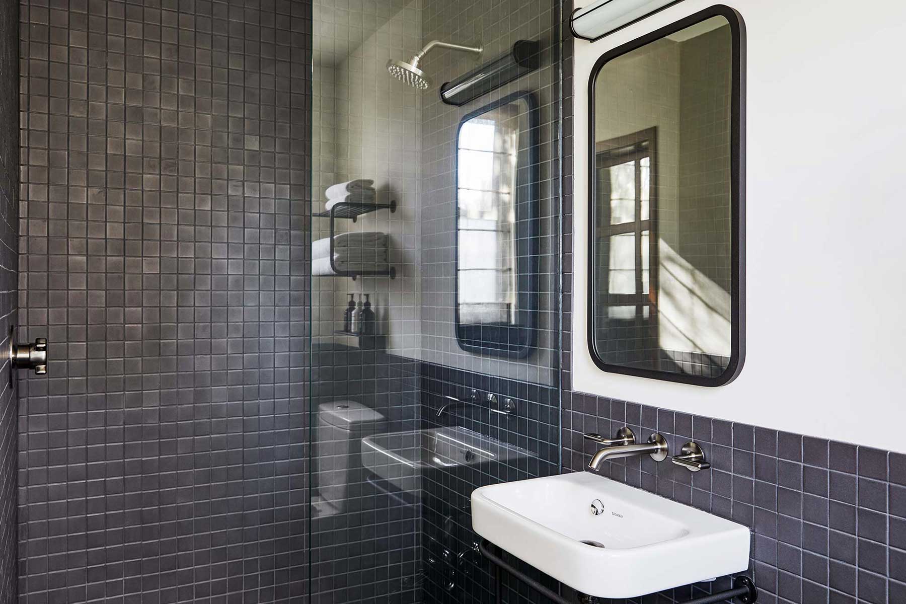 The ensuite bathroom features dark grey tiling and a walk-in rain shower