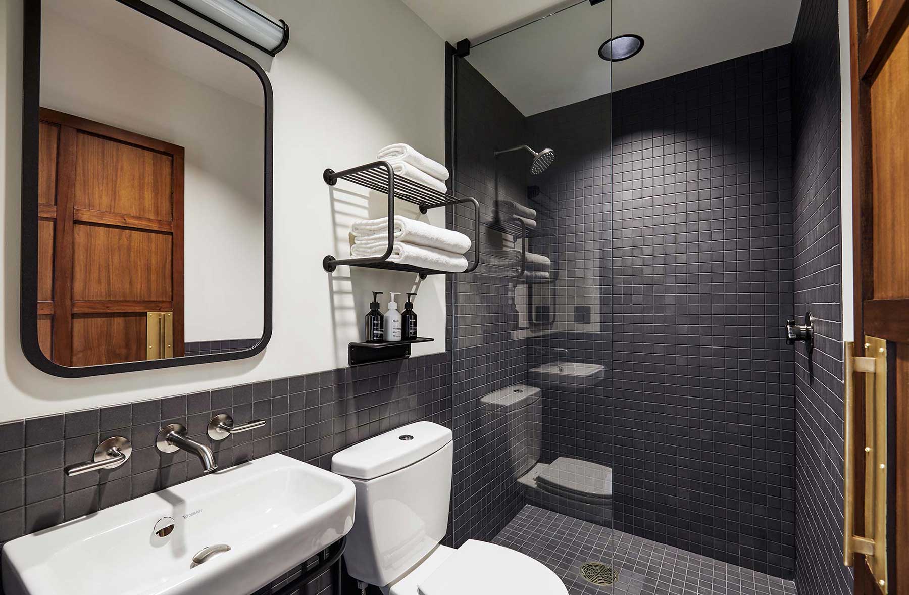 The ensuite bathroom has an industrial look, and includes a walk-in shower, towels and bathroom products