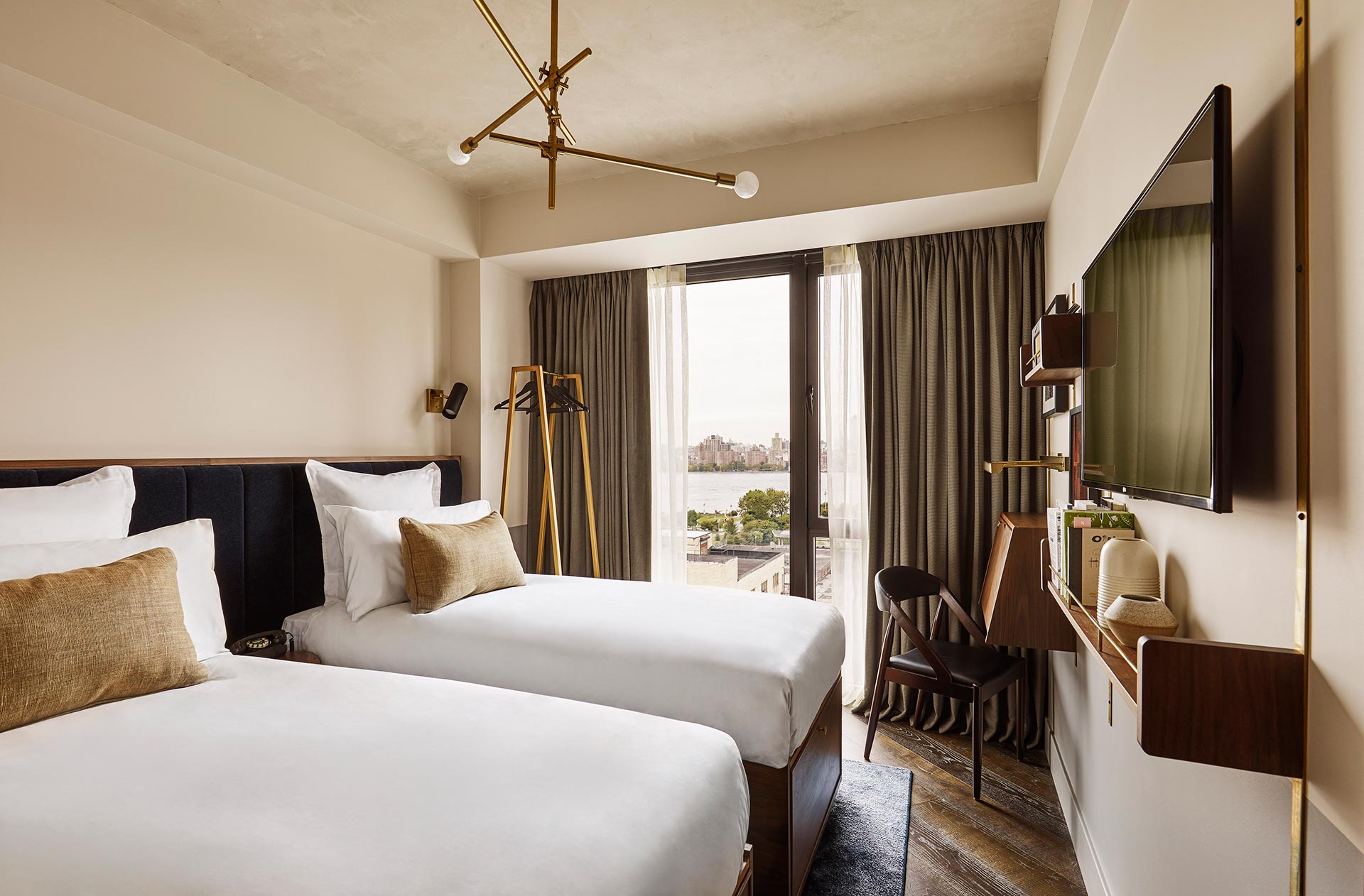 The two twin beds are separated by a table, and there's a hint of a view out of the window.