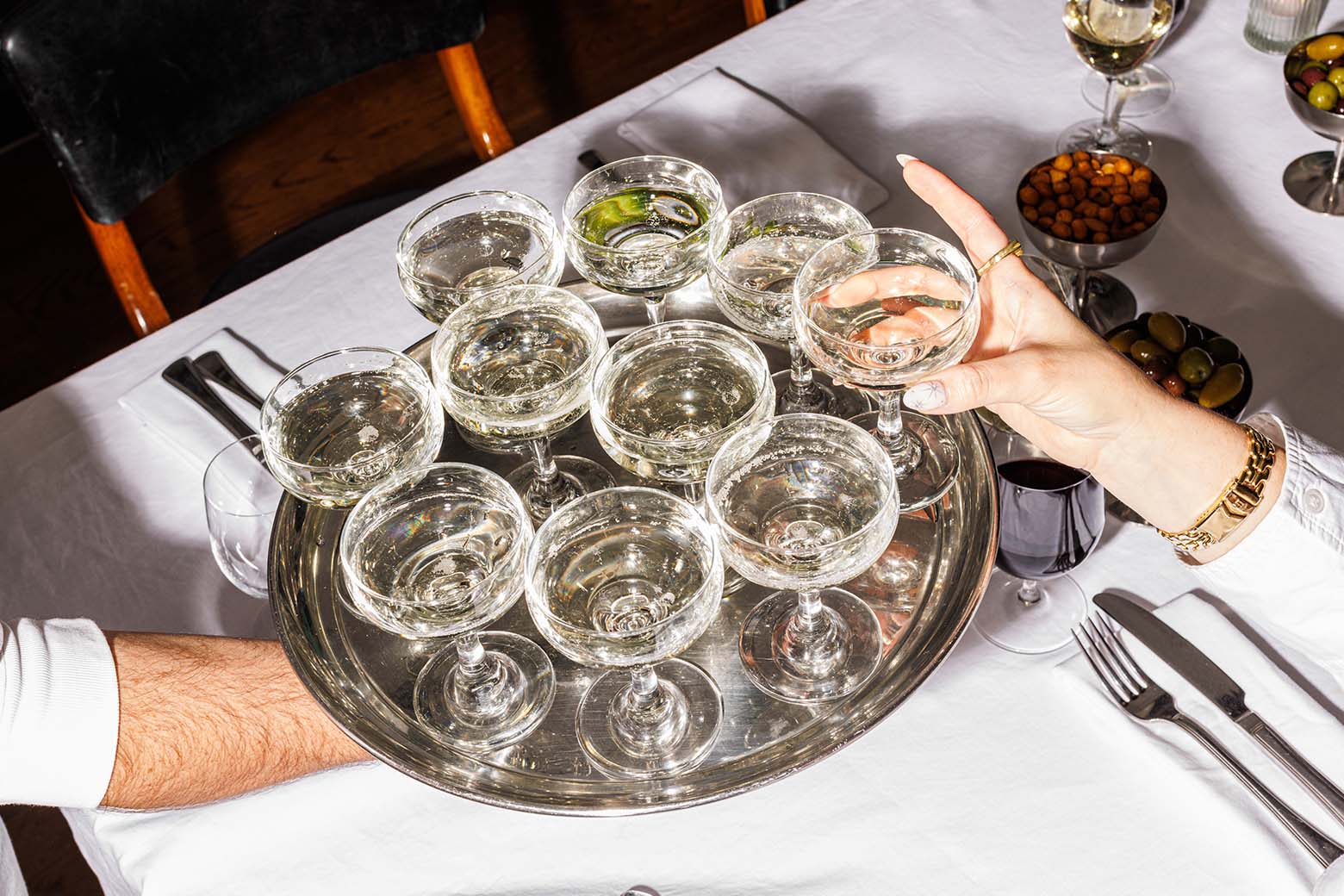 hand holding out a tray of drinks while another hand reaches out for one.