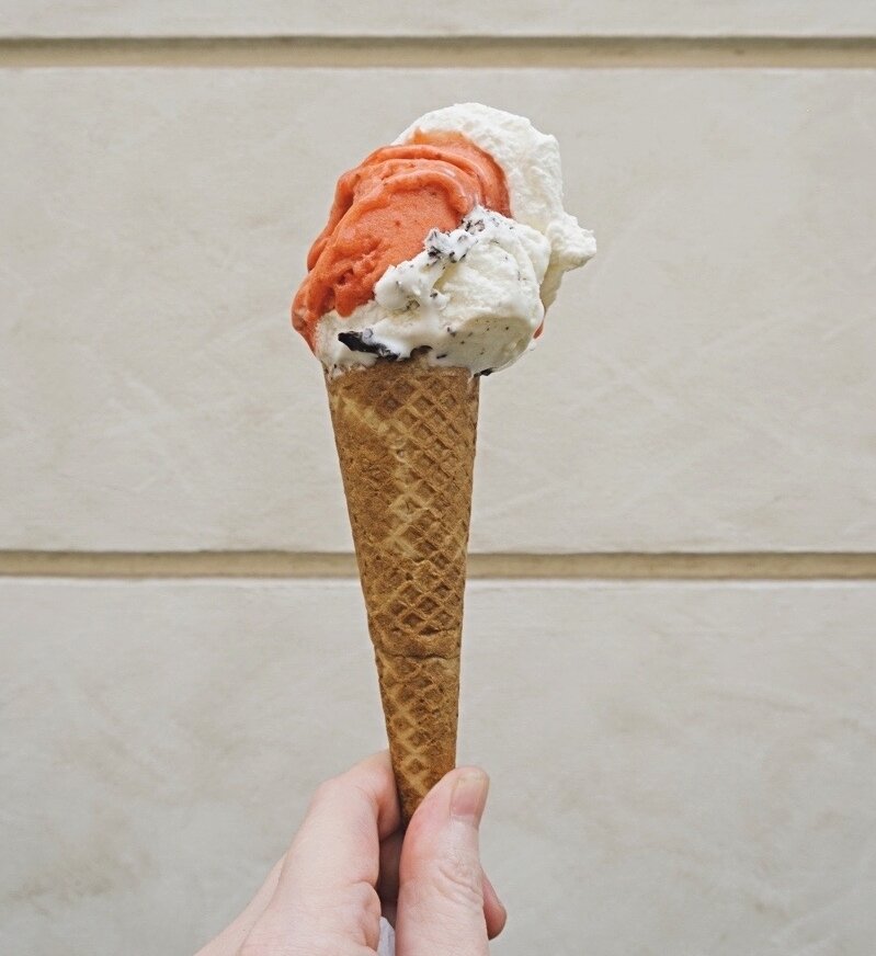 Ice cream in a cone held up by a hand