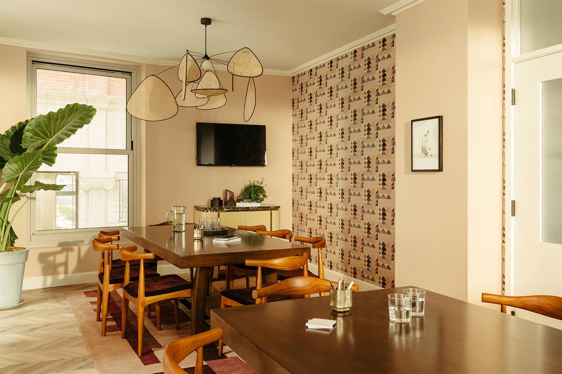 The room has two separate tables, each with eight chairs around it, and a TV on the wall