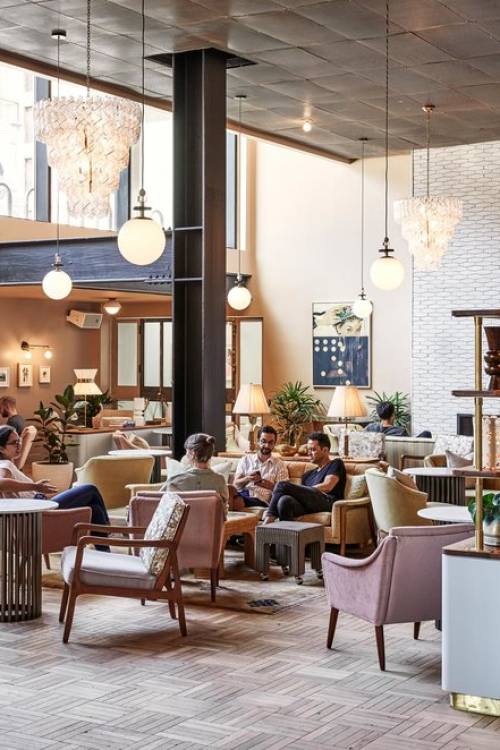 Guests sit in the large hotel lobby, some talking with friends, others reading