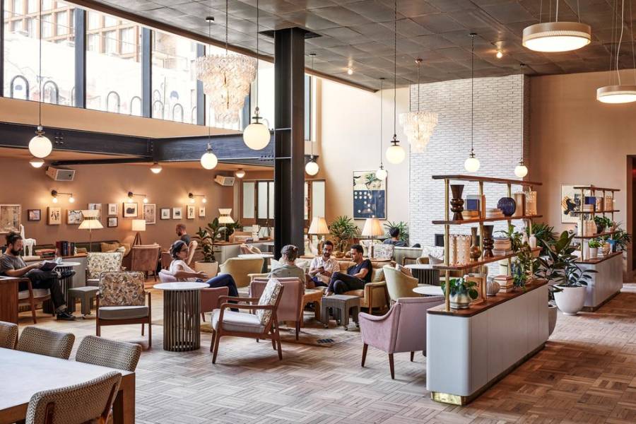 Guests sit in the large hotel lobby, some talking with friends, others reading