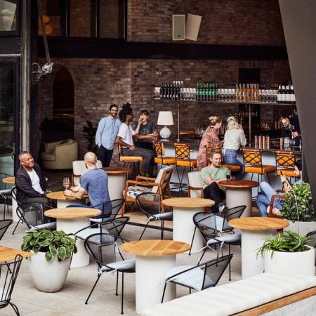 An outside courtyard area full of guests happily sitting at tables, drinking coffees and talking