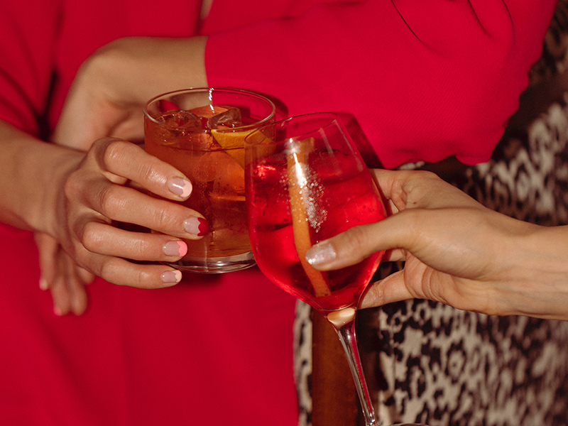 Un cóctel y una copa de vino tintinean en las manos de dos mujeres