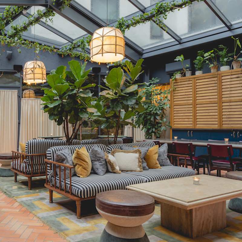 View of the covered courtyard interior, with sofas, and coffee tables surrounded by indoor plants.