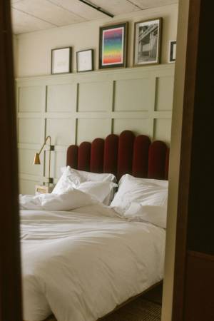 Hotel room showing bed with two pillows & duvet through a door