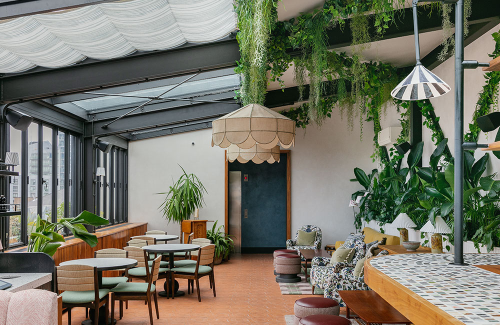 The restaurant has a lot of plants and a glass roof