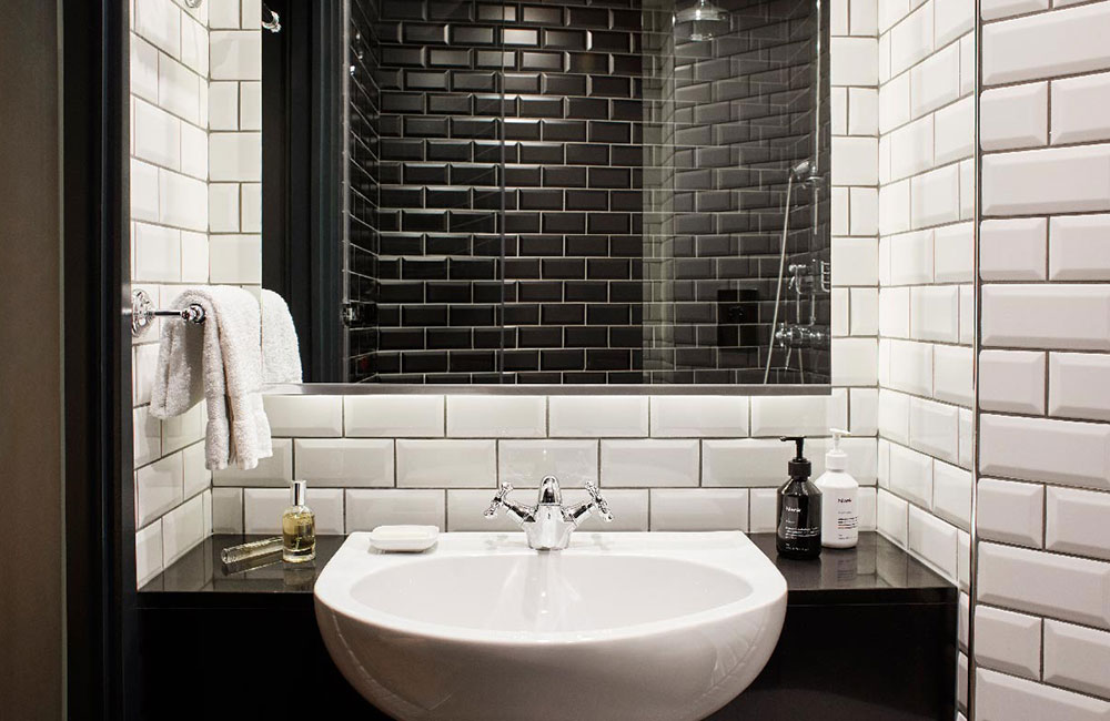 White metro tiles around the bathroom sink, including soap and other bathroom products