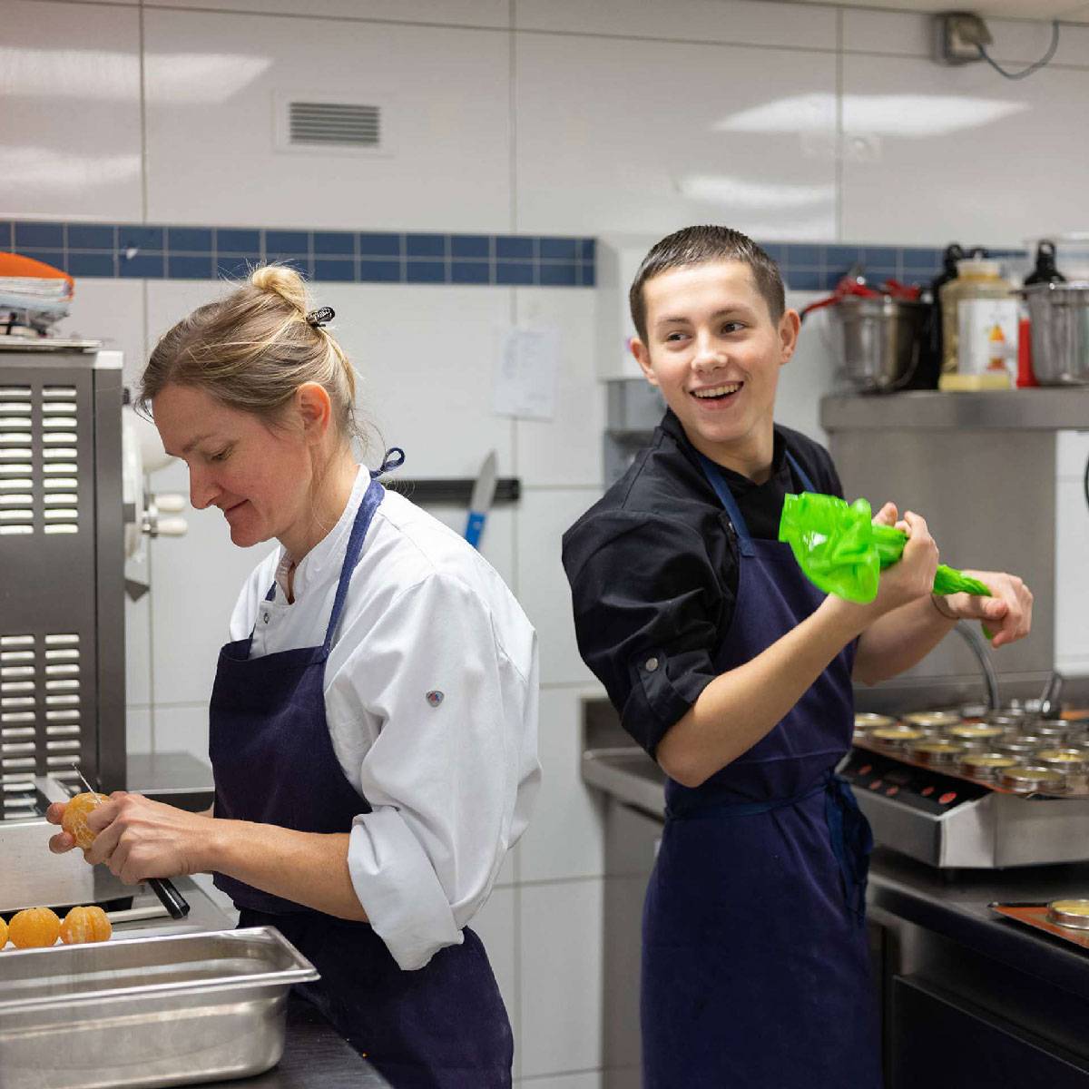 Two people working and laughing with each other in a commercial kitchen