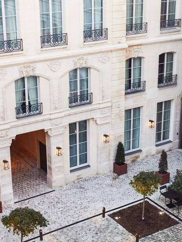 Courtyard in The Hoxton, Paris, with cobbled stones and neatly planted trees