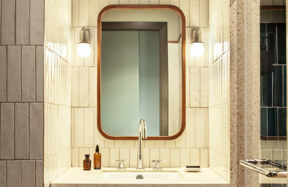 Sink area in the bathroom with mirror and lights either side