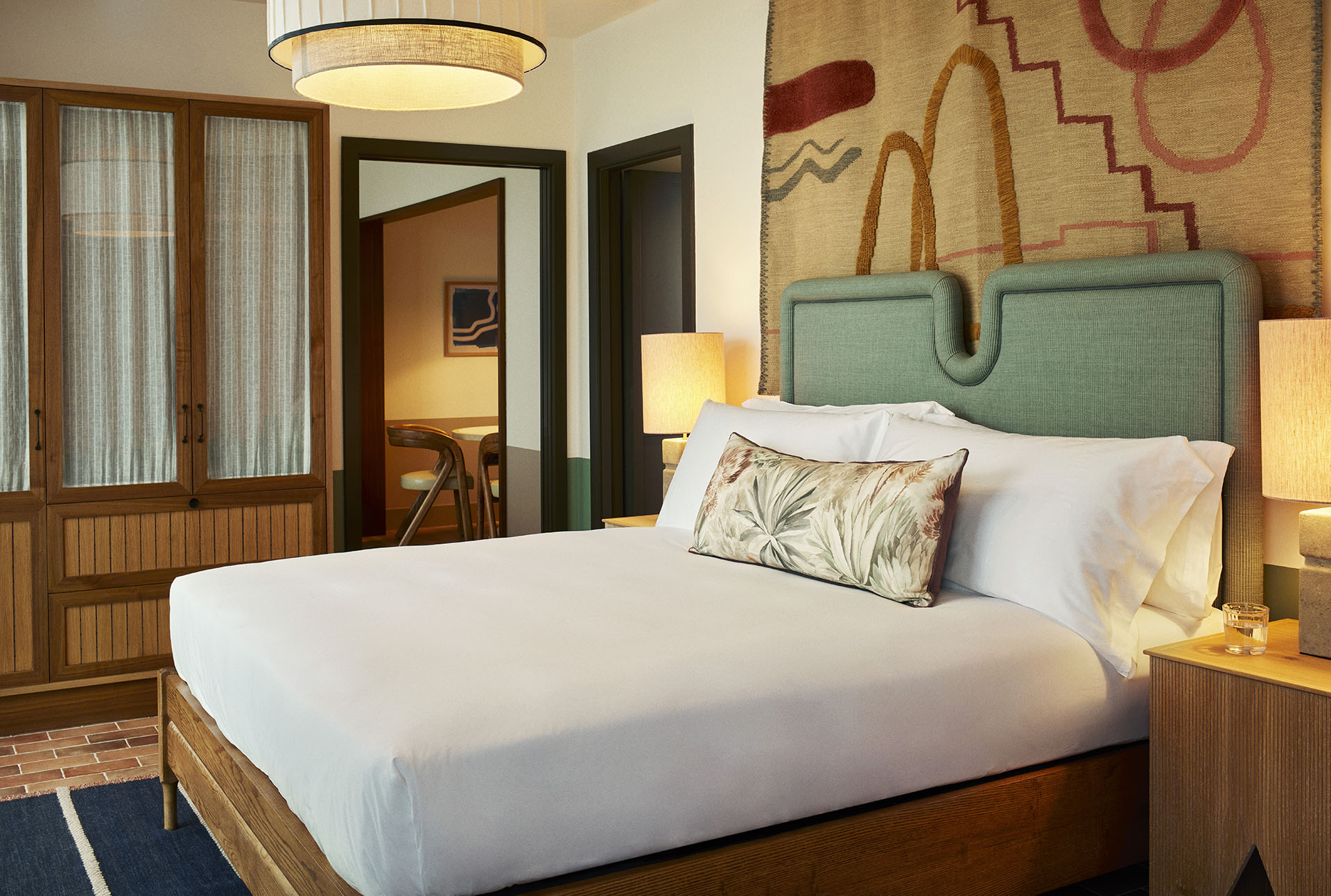 The bedroom has a large double bed with tables either side, with lamps on them