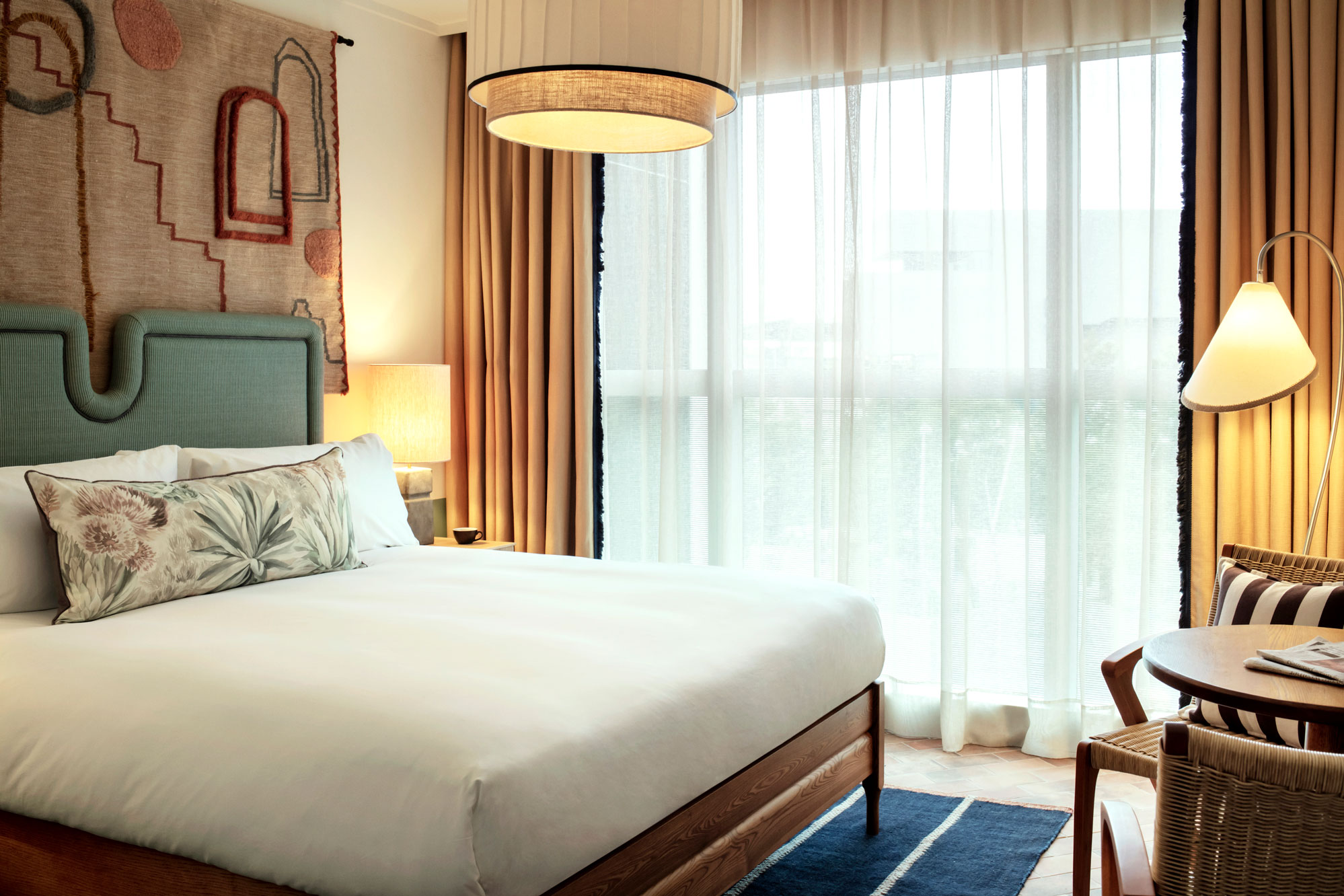 Large double bed in a hotel room with floor to ceiling windows