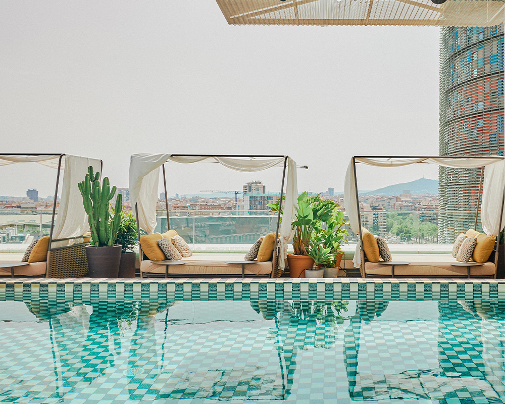 Rooftop pool with sun loungers, parasols and azure water.