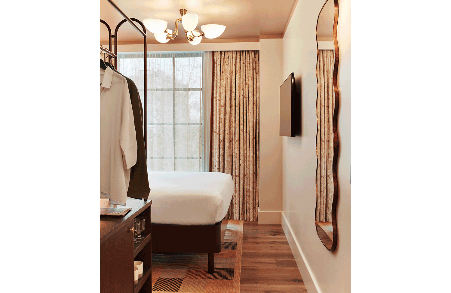 Snug room at our Shepherd's Bush hotel with comfortable bed, open wardrobe and sunlight through open window.