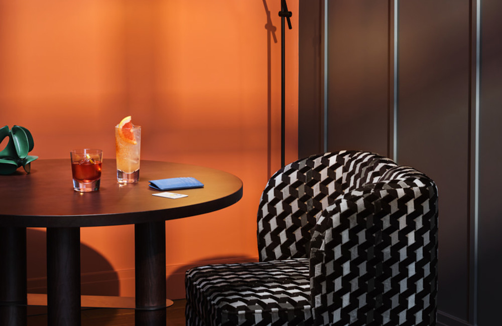 Armchair and a table with a refreshing beverage and hotel information on top.