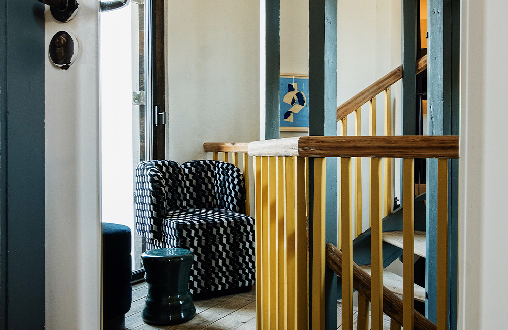 Stair landing with abundant natural light and pair of blue chairs.