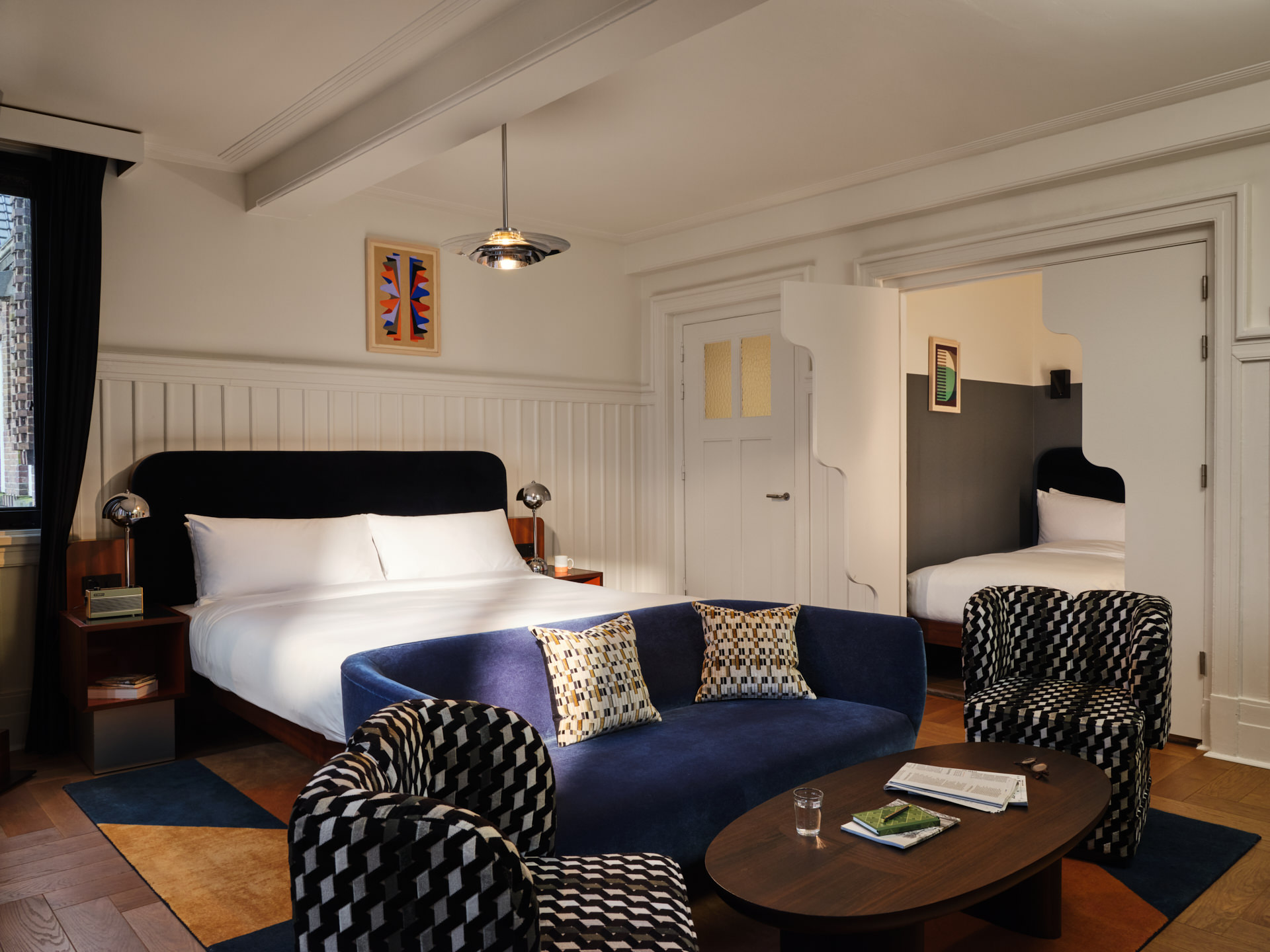 Room over view with a sofa, armchairs and coffee table in front of double bed.