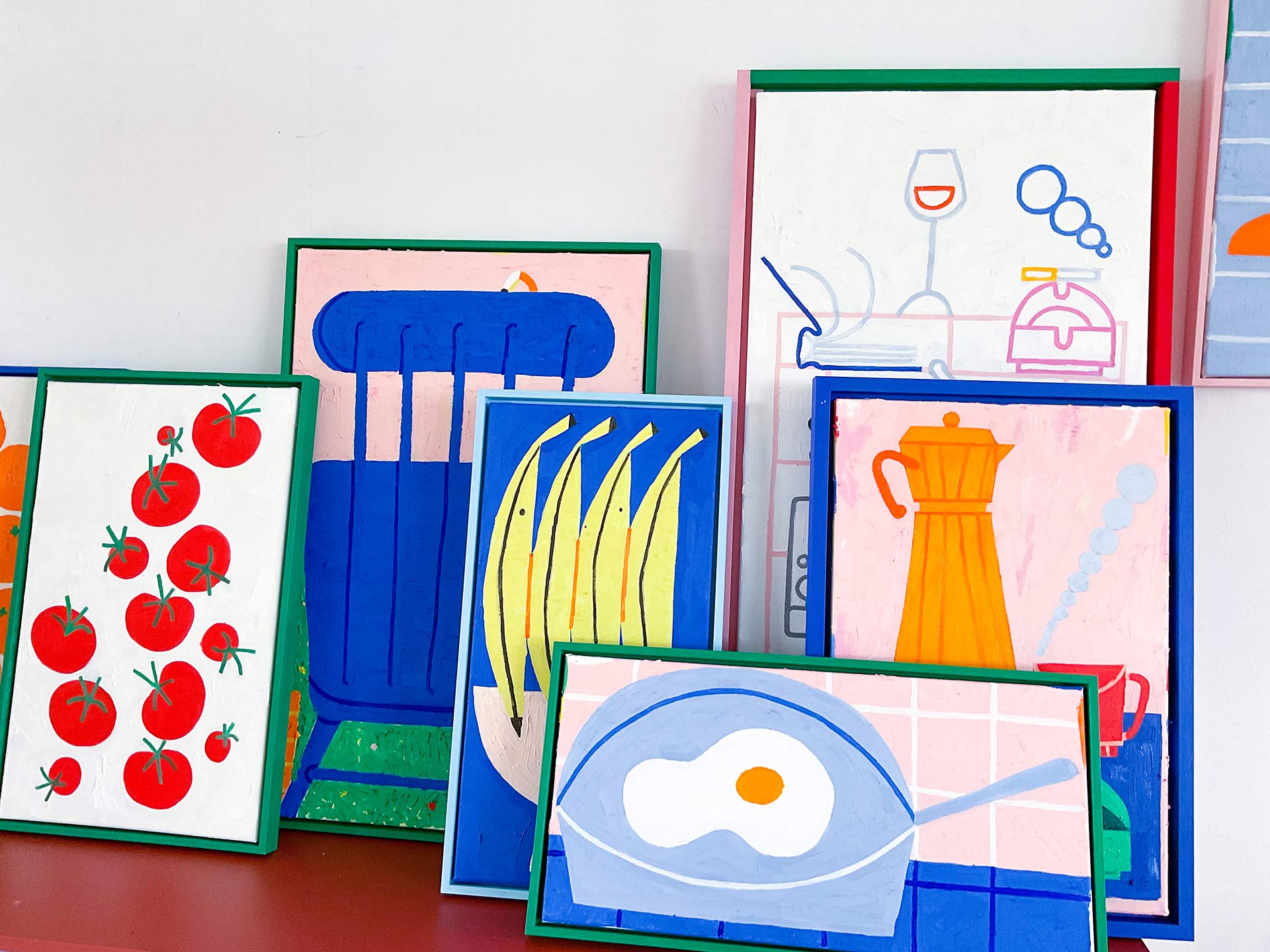 Bright and colourful paintings leant up against a wall.