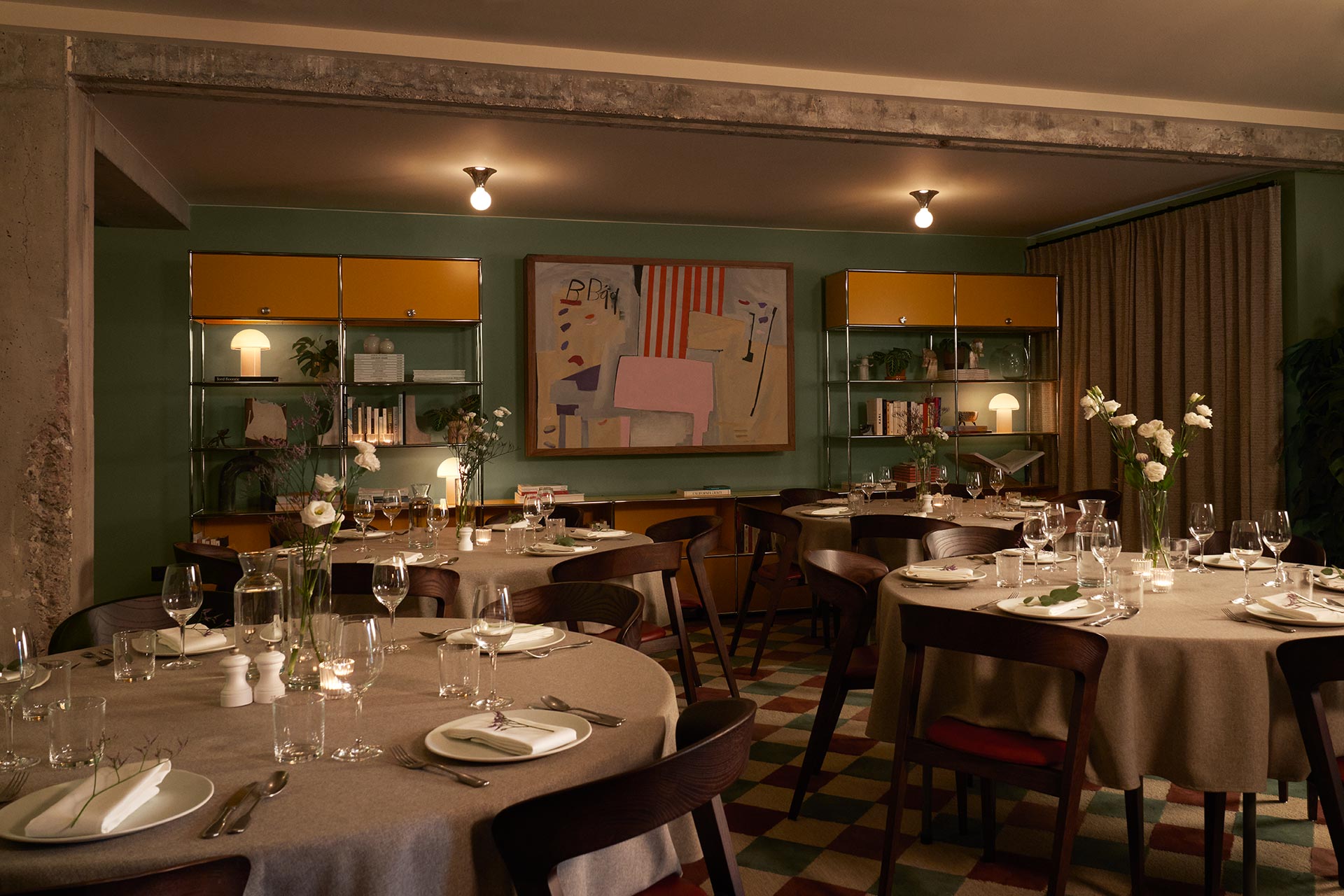 Round tables laid out for an evening meal in The Living Room.