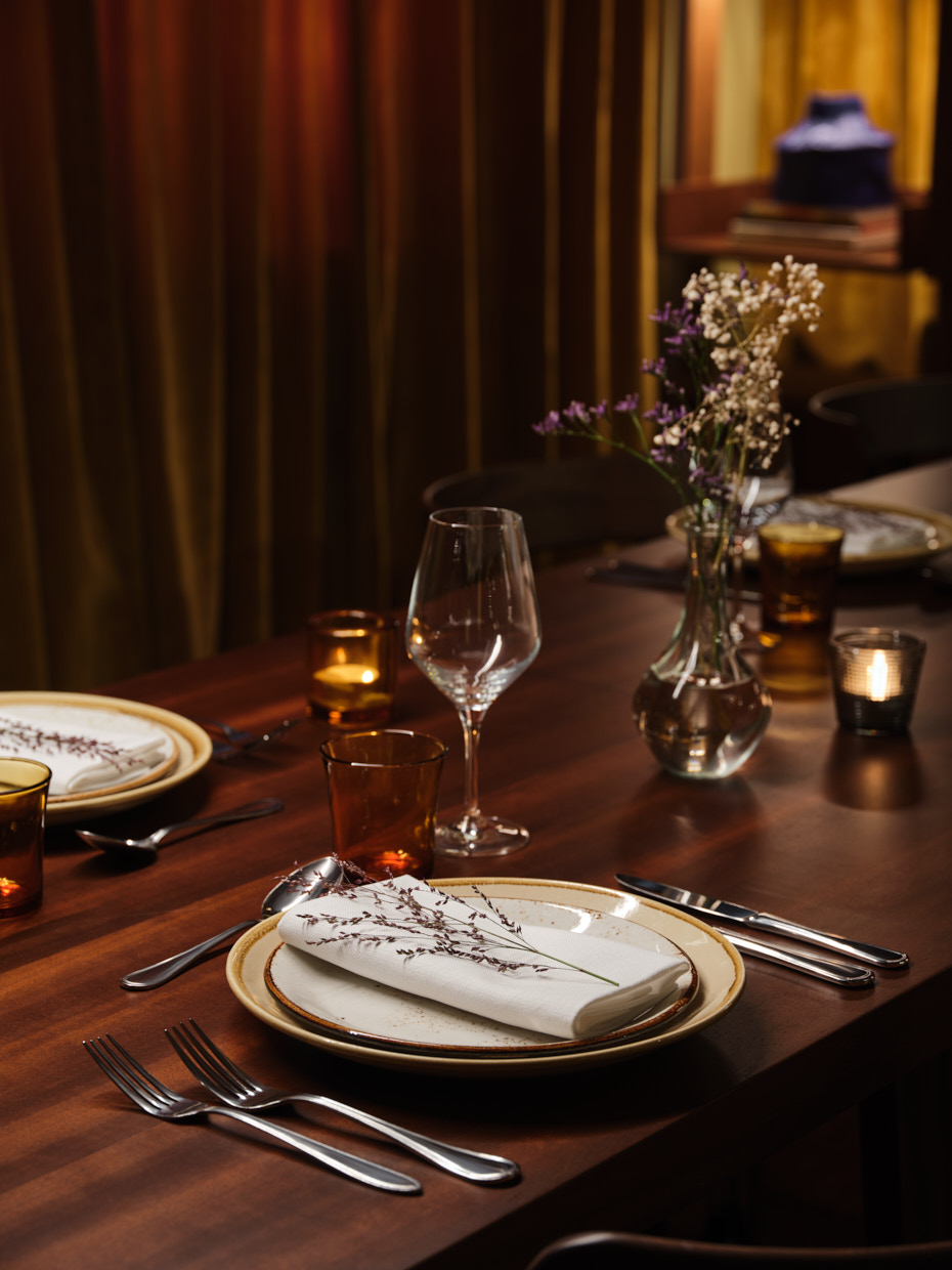 Place laid for a diner with a wine glass, napkin, cutlery and more.