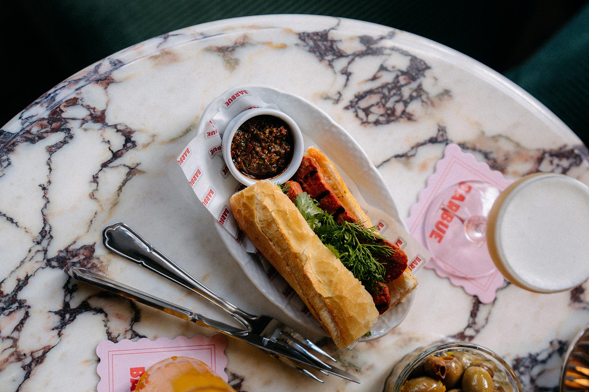Bar snacks, sandwiches and cocktails rest on a round marble table