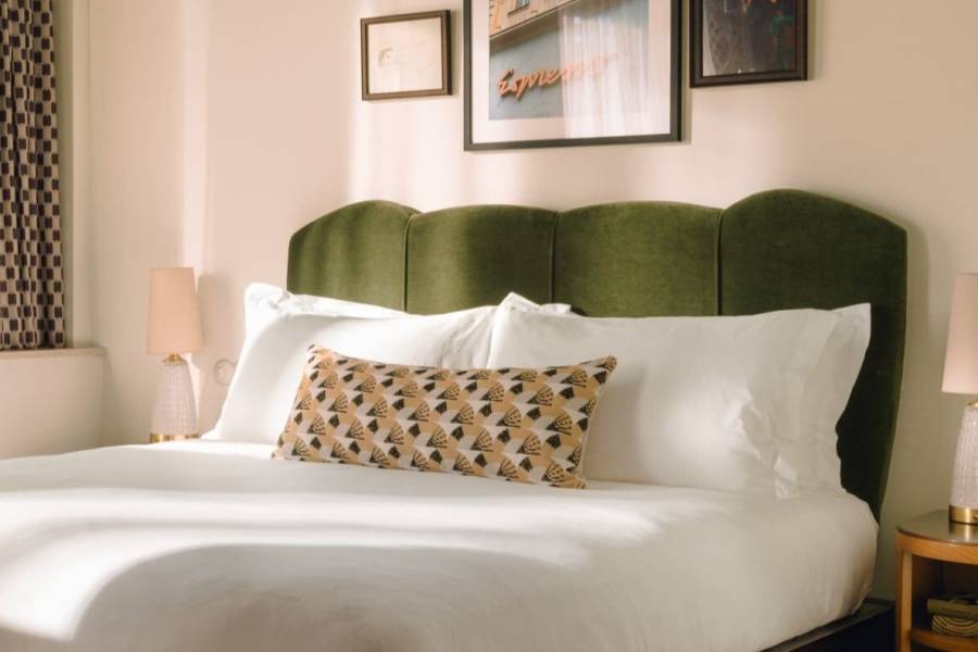 Large view into the room, with king size bed with green headboard.