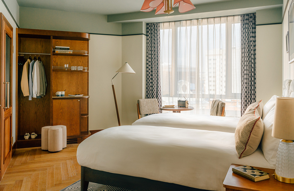 Overview of the roomy room with twin beds and large open storage space opposite the beds.