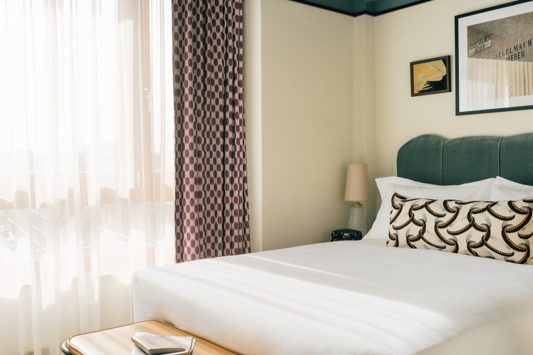 Side view of double bed with a side table and large window.