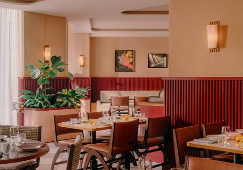 The interior of the bouvier, with tables and chairs and a large window, gives natural light.