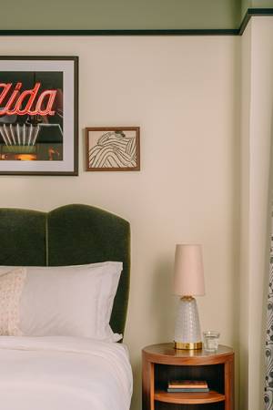Bedroom interior with tall window, lots of art on the walls and comfy bed