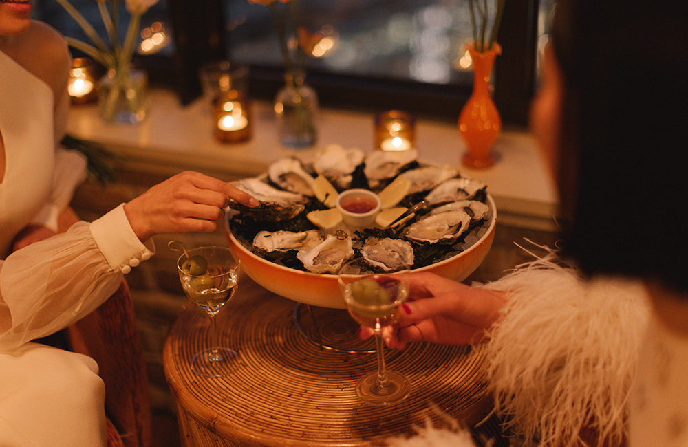 Two female diners sample an ice-tray of oysters
