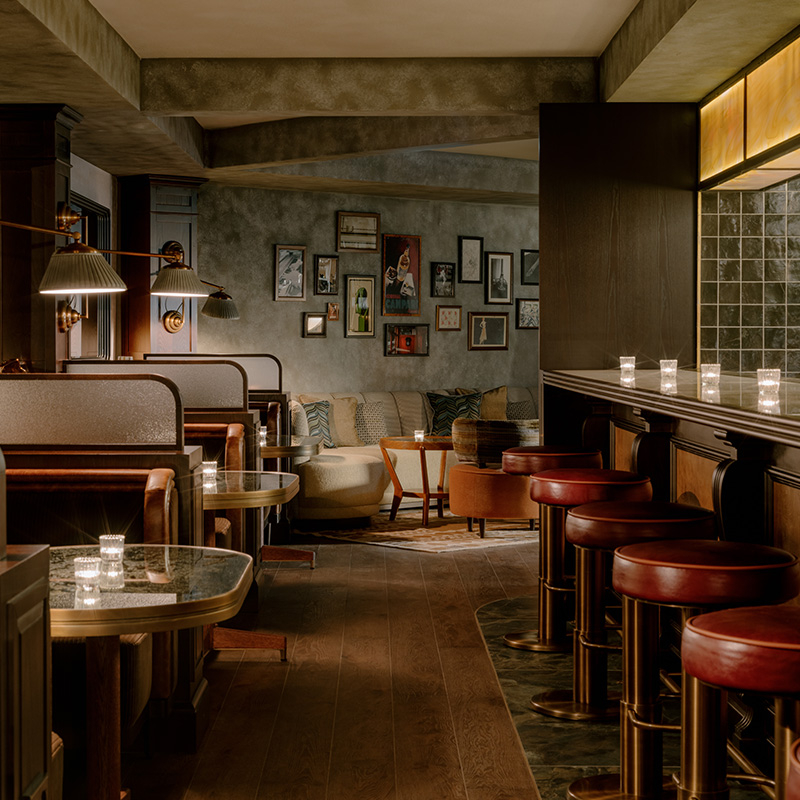 view of a long aisle with private booths on the left and a bar with barstools on the right