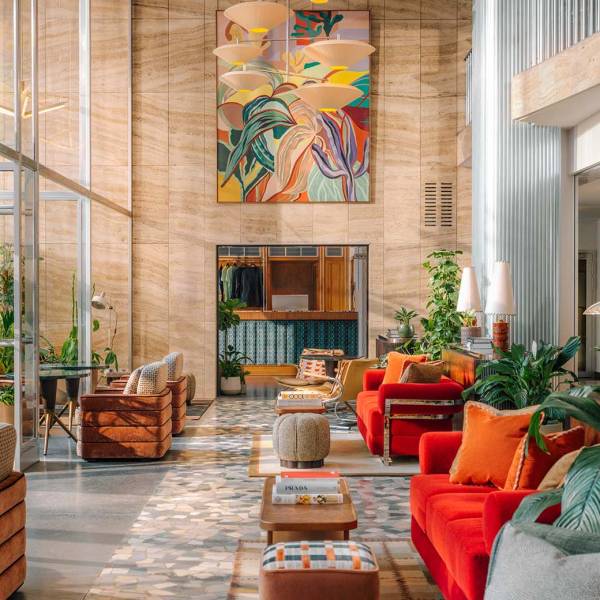 View of the Hoxton Vienna lobby, large windows and natural light reflecting on to the furnitures like bright velvet sofas coffee tables and soft armchairs.