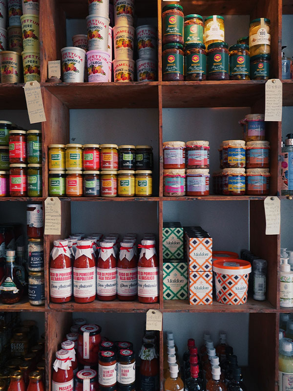 Shelves displaying a variety of canned and jarred foods in Sforno store.