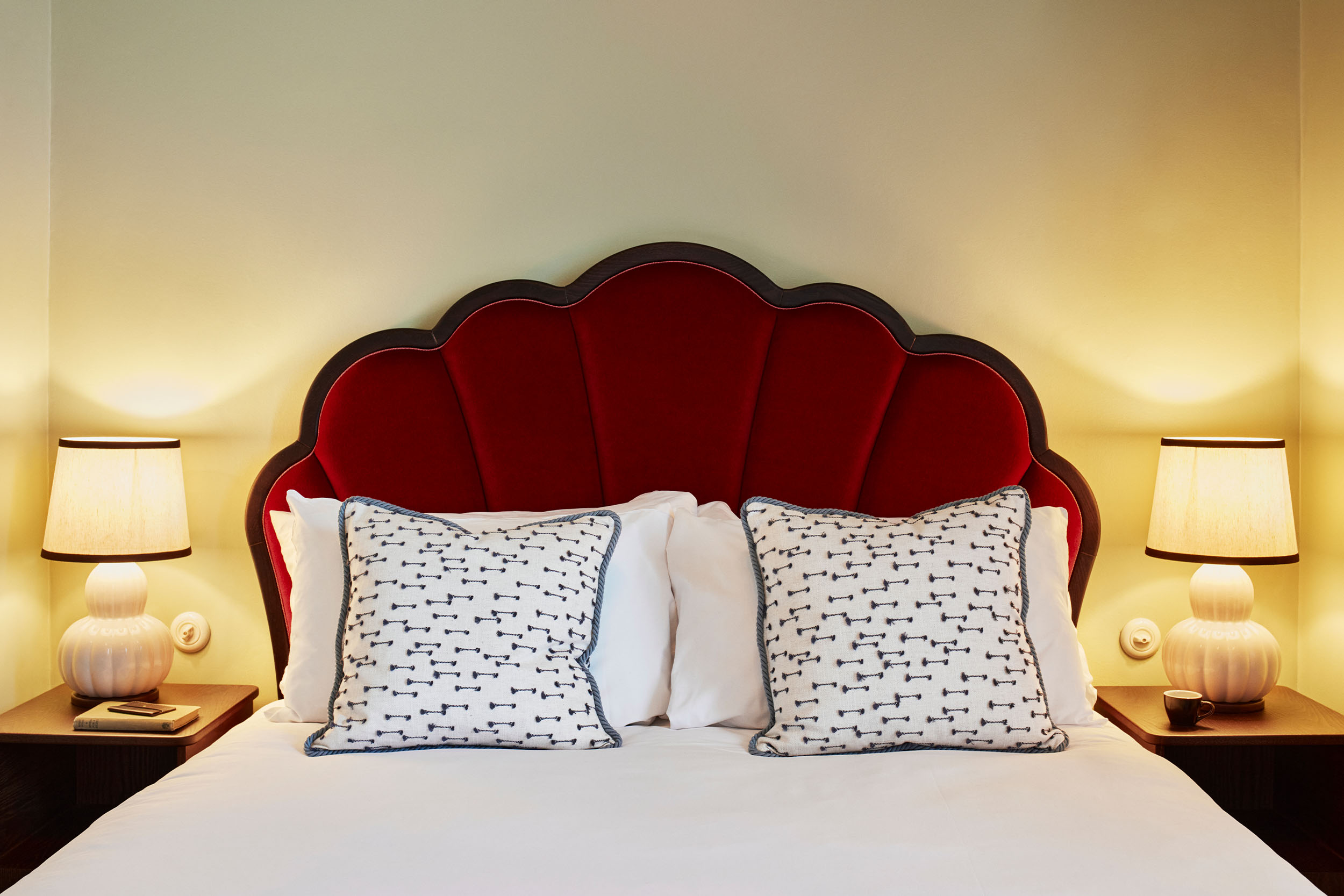 Front view of a double bed in a room at Hox Edinburgh with a stylish red velvet headboard.