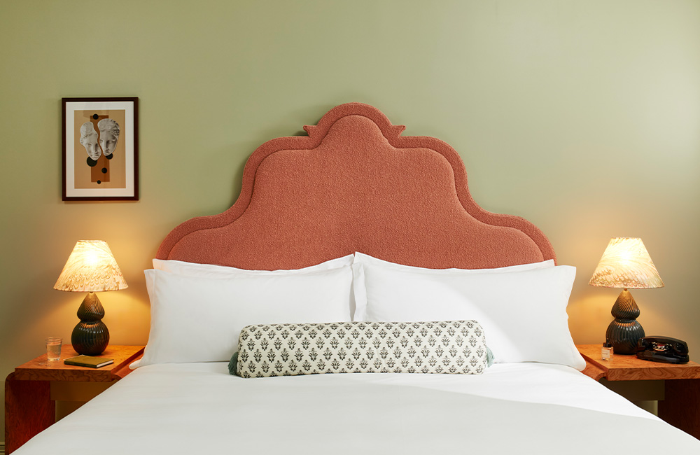 View of a soft pink super king-bed headboard with a bedside table on each side.