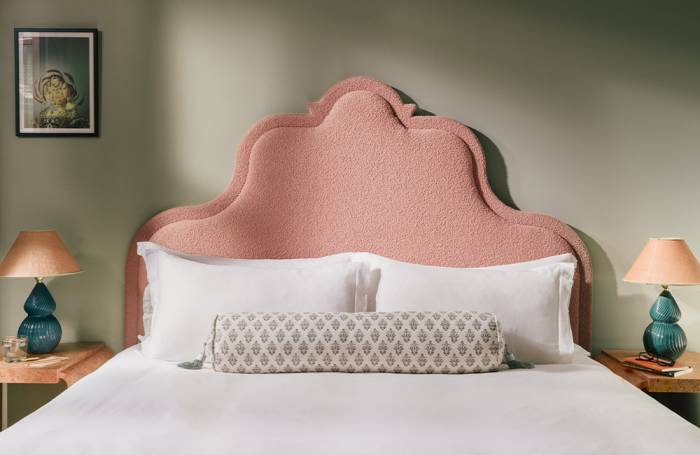 View of a soft pink super king-bed headboard with a bedside table on each side.