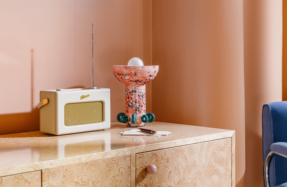 Radio and a coral and pink glass lamp resting on a table.
