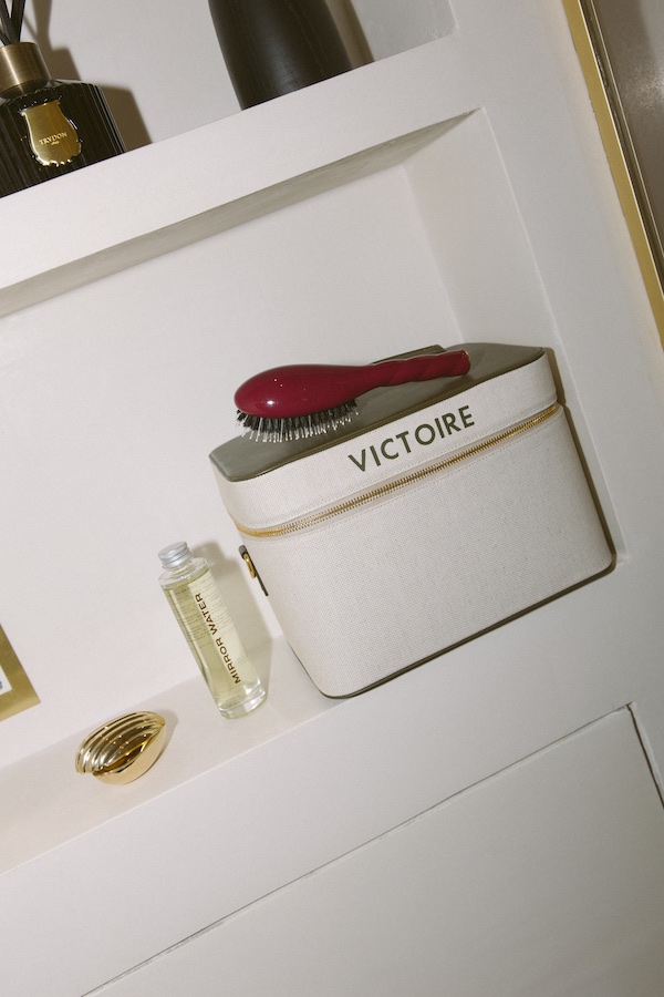 Photos by Nic Ford.close up of bookcase shelf with a vanity case with red hair brush resting on top of it.- The Localist, Hoxton Hotels.